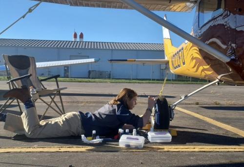 Lucy paints the tire of her plane before a competition.