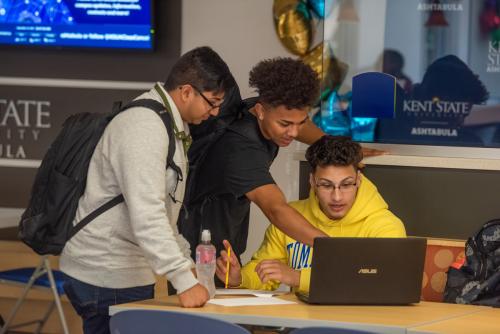 Three students work together around a laptop in the ����Թ� State Ashtabula student commons.