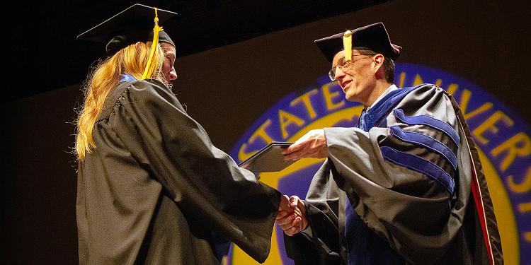 Dean Bill Ayres (right) shakes hands with a female student at commencement