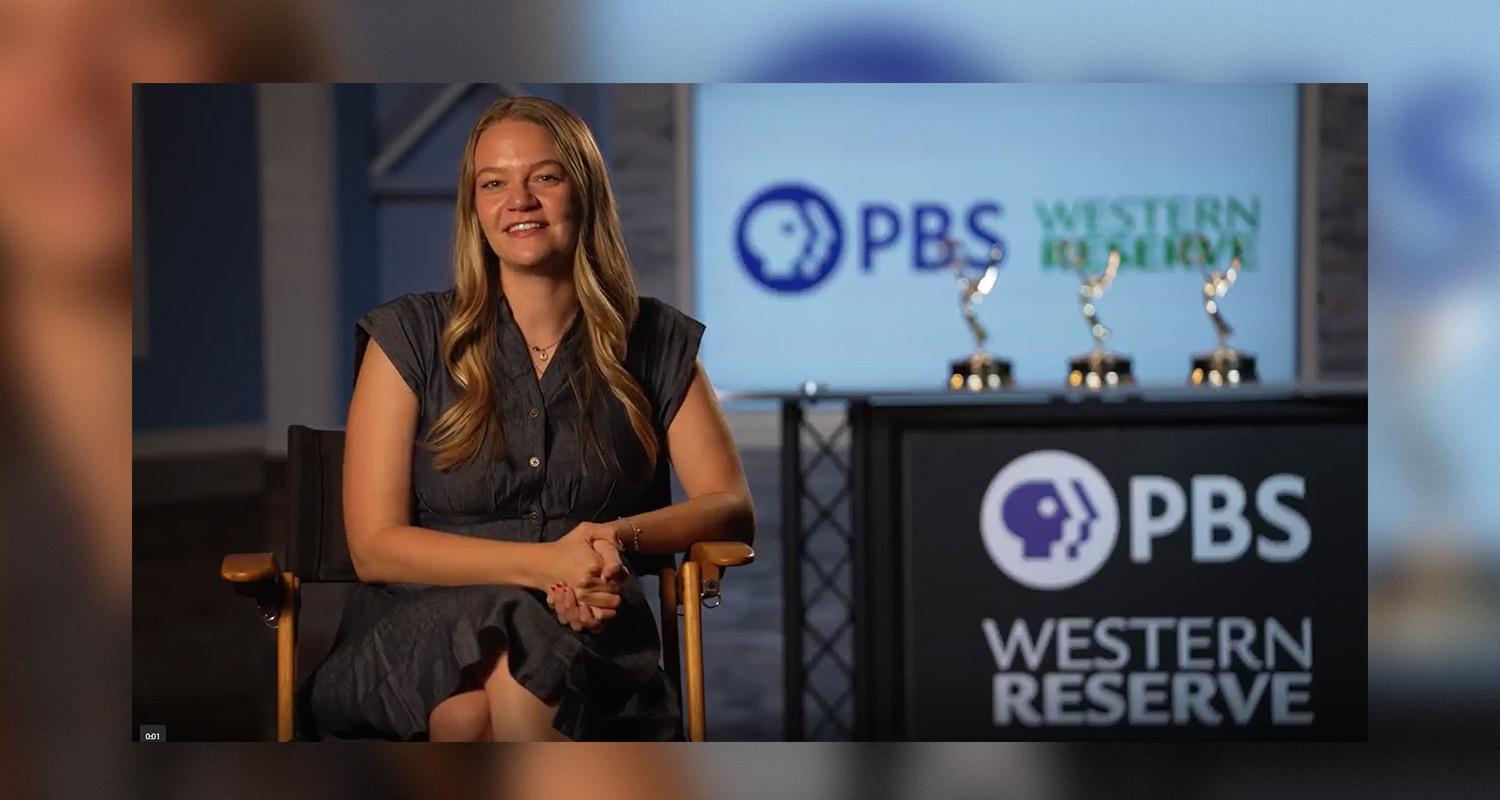 Alumna Sophia Gillespie sitting next to a PBS Western Reserve sign