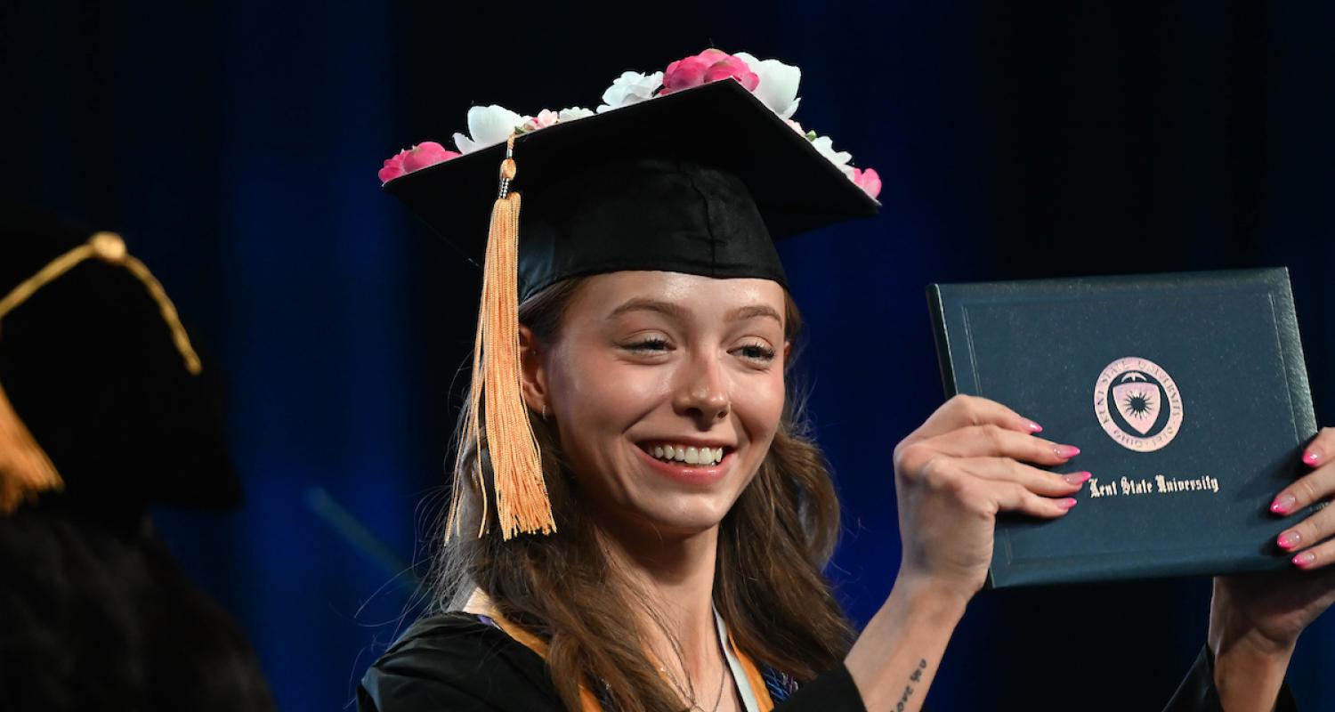 A new 51���� graduate proudly holds up her diploma during her commencement ceremony.