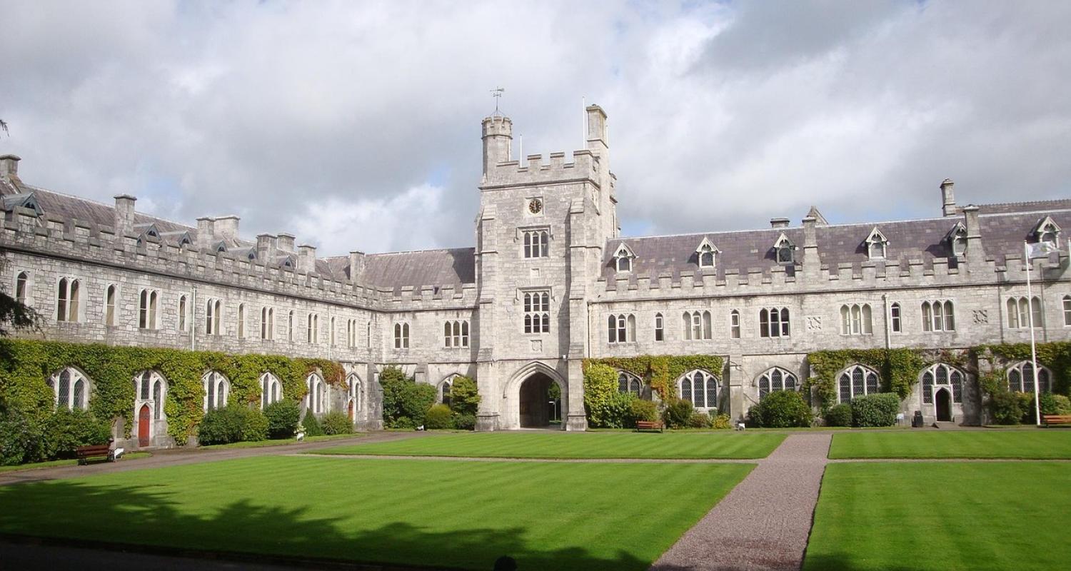University building, cloudy skies, green field.
