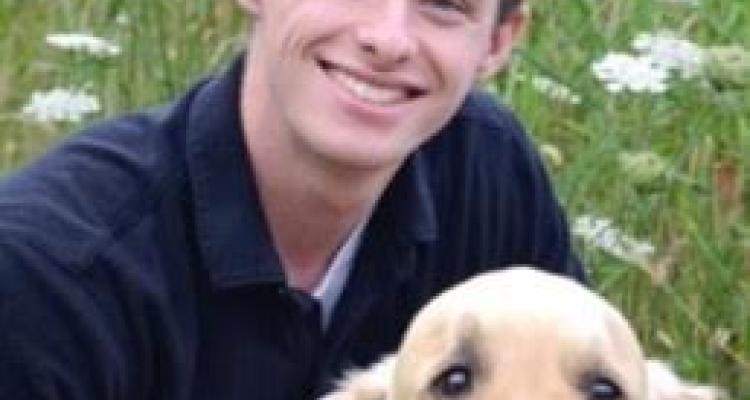 Senior Honors College student Alex Hyde, posing for photo with dog.