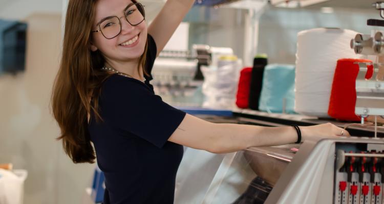 Adelynn Prushing stands in a studio while holding different fabrics.