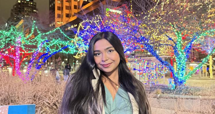 Shashwati Sikder Sharaya posing for picture in front of a building with lights in the background. 
