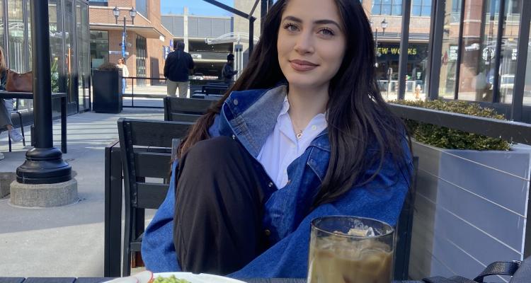 Honors Student Sophia Daher sitting at a table enjoying a meal.