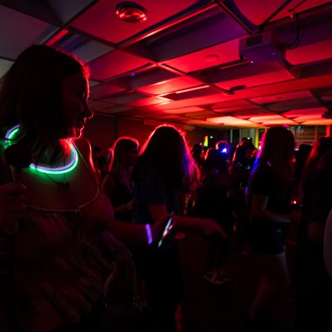 Students dance in the dark while wearing glowing accessories.