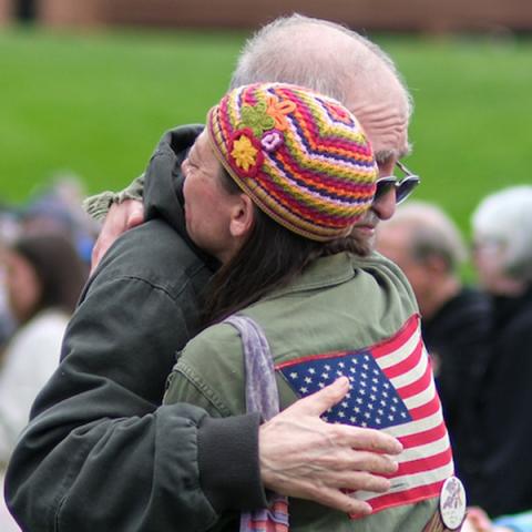 Friends hug while members of the Kent State University community and visitors gather on the Kent State Commons for the annual May 4 Commemoration to honor those who were killed and wounded on May 4, 1970. (Photo credit: Bob Christy, Kent State University)
