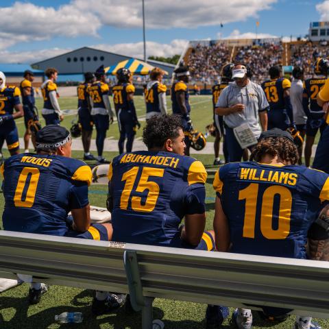 Ģ����ý football players rest on the bench during a home game in fall 2025