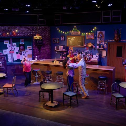 actors play roles on a stage decorated to look like a dive bar.