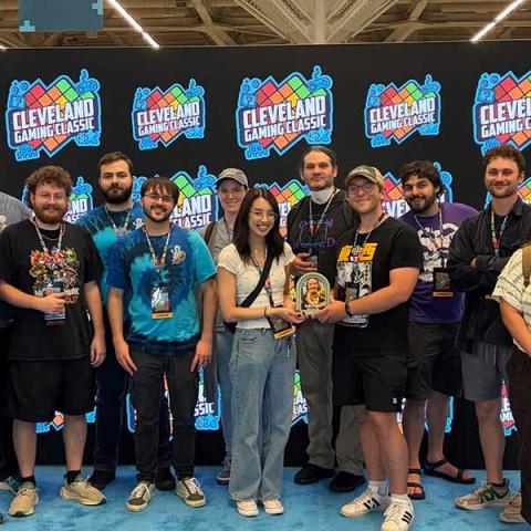 A group of attendees poses together in front of a Cleveland Gaming Classic backdrop at the gaming convention.