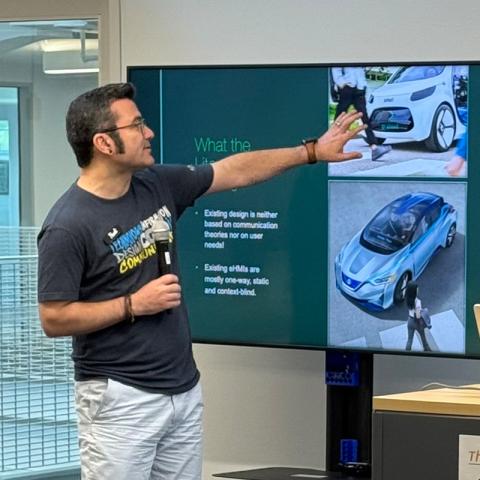 Design Innovation Fellow Hadi Rahmati points to large monitor and explains autonomous car feedback