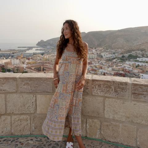 Student in long dress with a coastal city view behind them