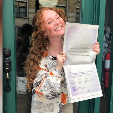 Grace Petitjean holds newspaper with ad copy she wrote