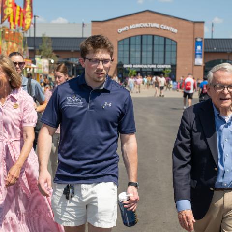 �������� student Nathan Smith (center) walks with Ohio first lady Fran DeWine (left) and Ohio Gov. Mike DeWine (right) at the Ohio State Fair.