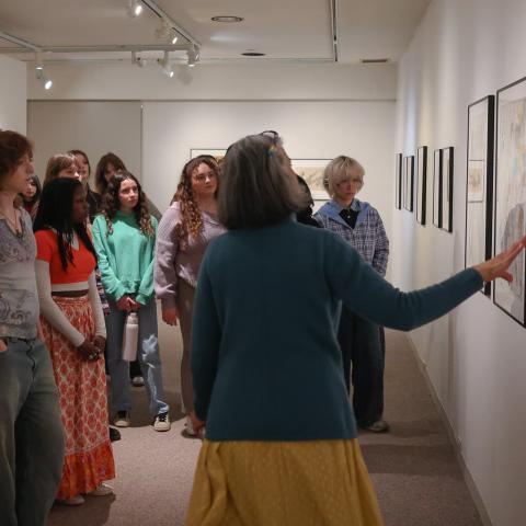 Professor Archana Mehta pointing to Leroy Neiman exhibit artwork for students