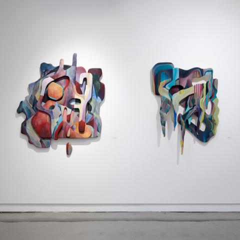 two colorful wooden sculptures on a gallery wall