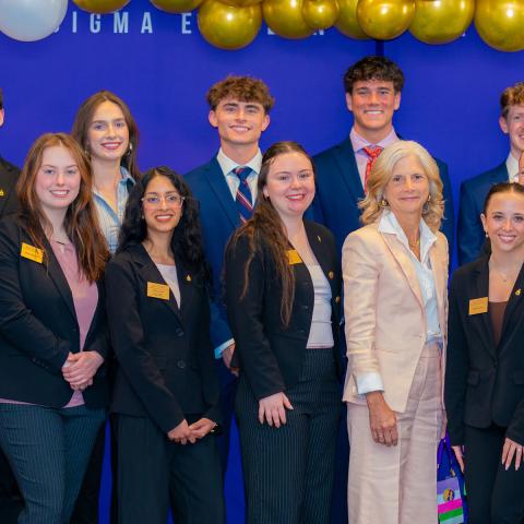 Student members of PSE posing infront of competition banner, pictured with KSU Professor Kelly Blay. 