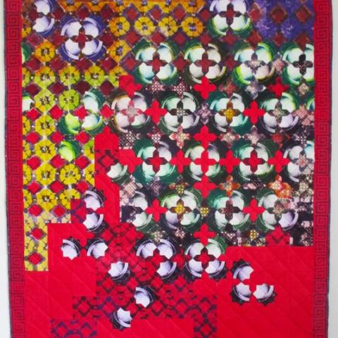 An art quilt composed of solar plate prints, boasting vibrant reds and greens