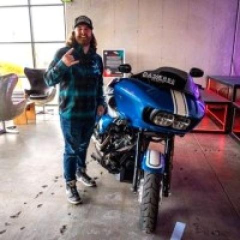�Ը������� alumnus Tony posing in front of a motorcycle.
