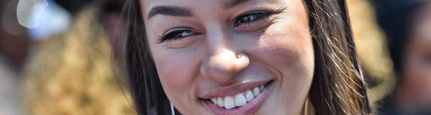 Female student smiling in cap and gown at graduation.
