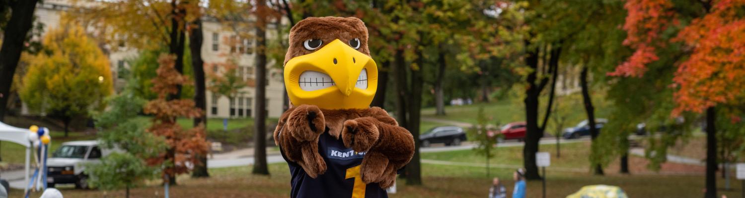 Kent State University’s mascot, Flash, standing in the back of a white pickup truck during the homecoming parade, pointing directly at the camera.