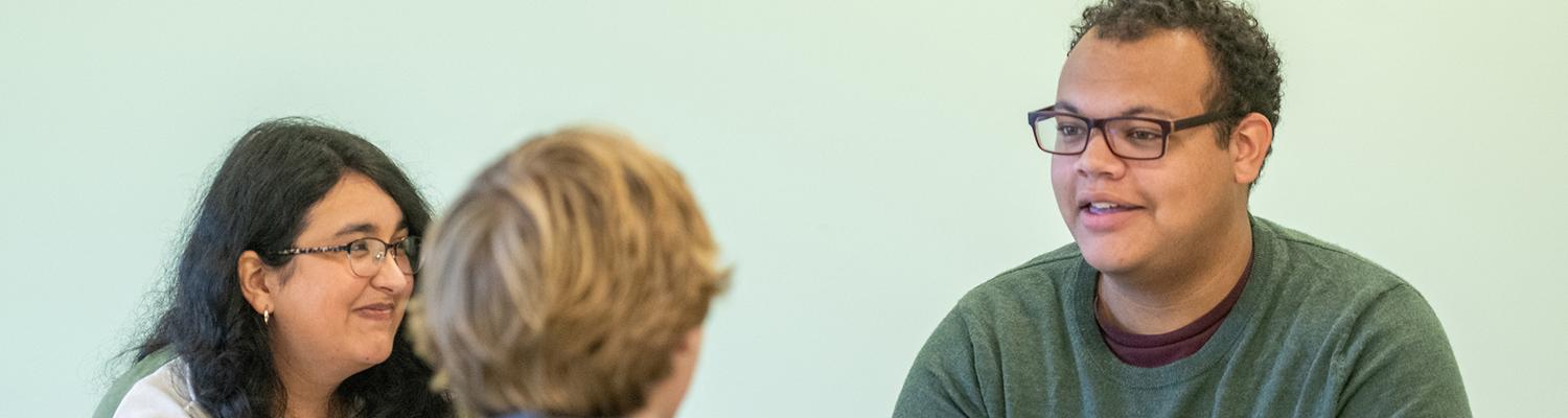 A female and a male student speak in a class with another male student