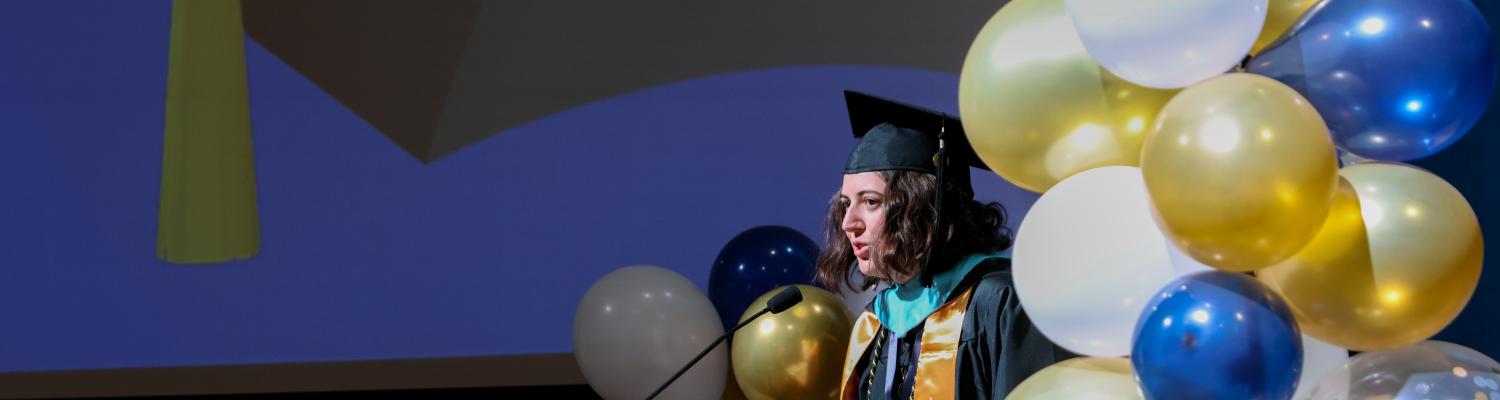 Higher Education Administration M.Ed. student and president of GRASSP Brie Brullo addresses the crowd during her closing remarks at the annual hooding ceremony.