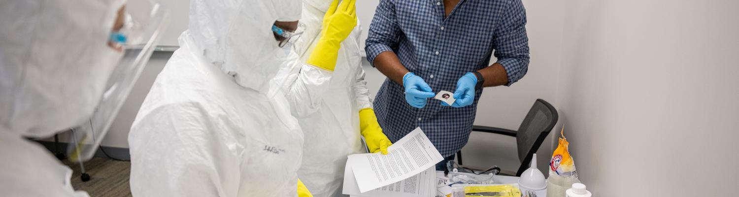 Three technicians in a cleanroom lab