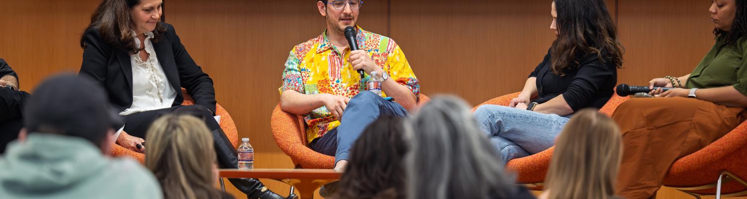 Panelist sitting in front of a group of people having a discussion. 