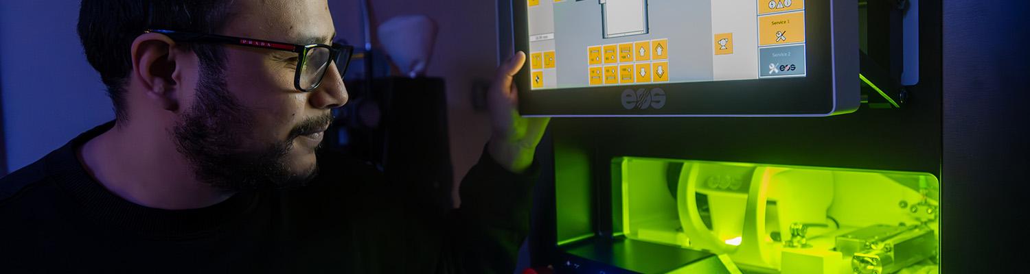 Graduate Student observing a metal 3D printer