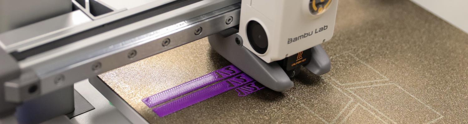 A close-up of a Bambu Lab 3D printer in operation, printing with purple filament. The printer nozzle is laying down layers on the build plate, forming two rectangular objects with visible infill patterns. The textured build surface also shows faint outlines of previous calibration prints.