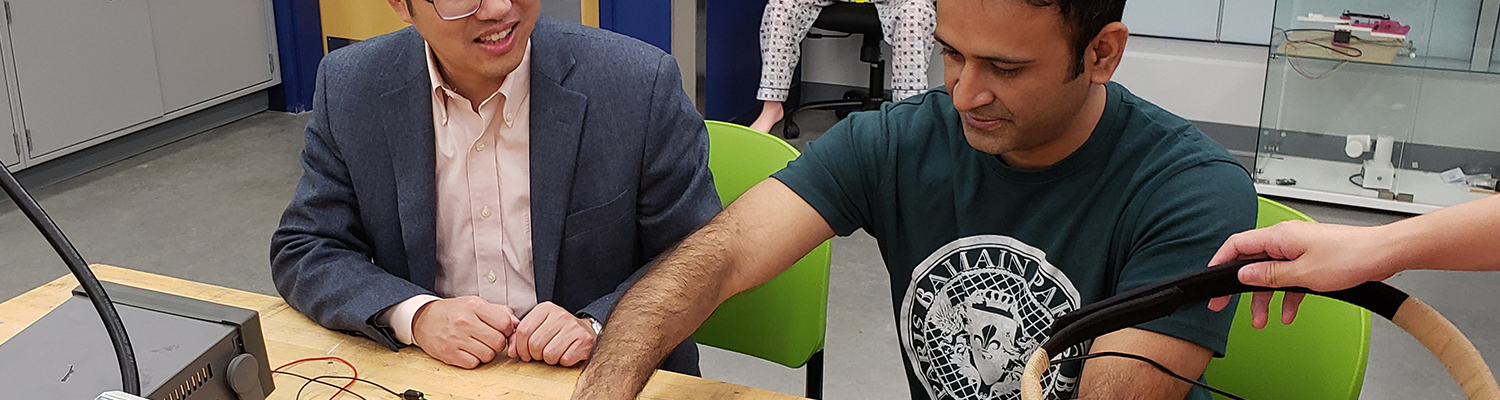 Professor Tao Shen, Ph.D., helps a student test a circuit at a work table in the Advanced Medical Robots Lab.
