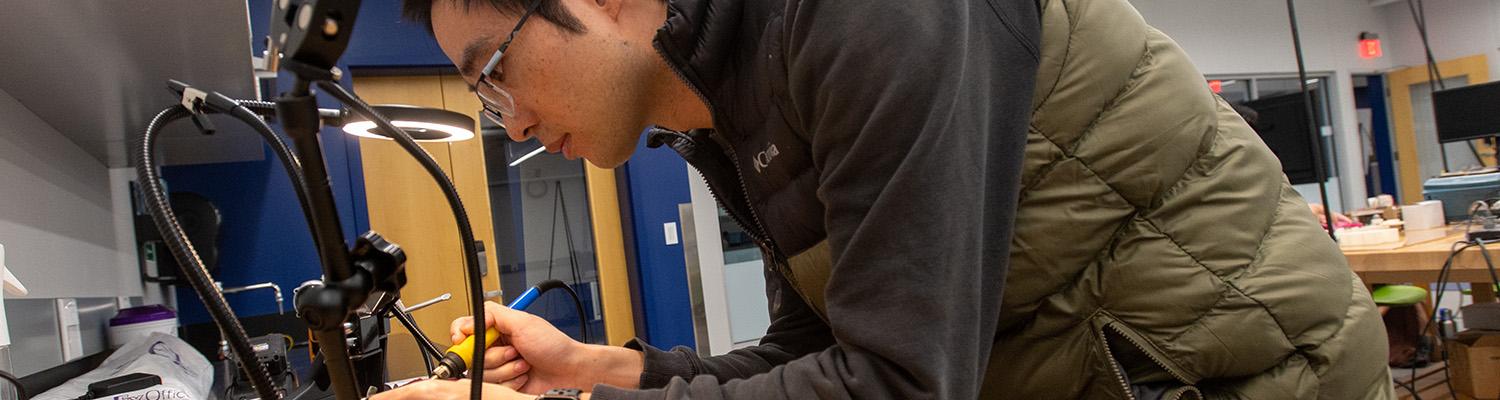 Dr. Tao Shen solders an electrical component at the Advanced Medical Robot Lab