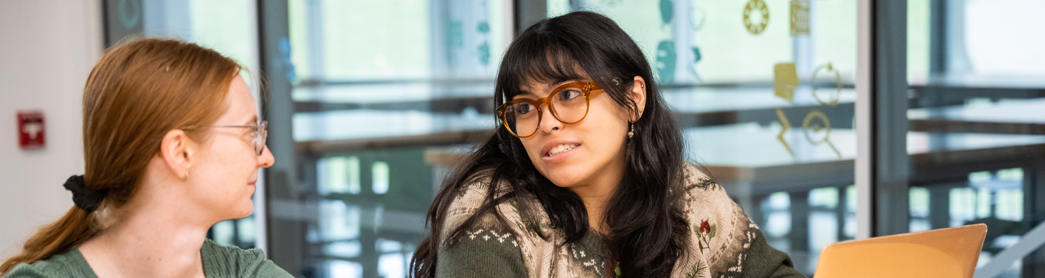Two students talking in a classroom setting.