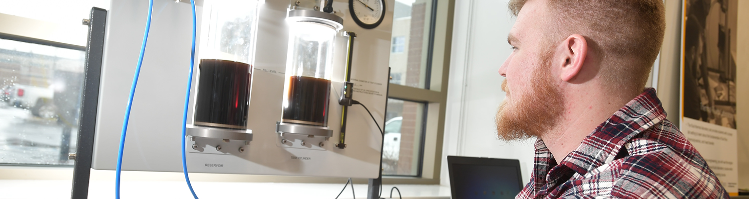 A student records the levels of two cylinders containing liquid in an apparatus used to observe the properties of Boyle's Law.