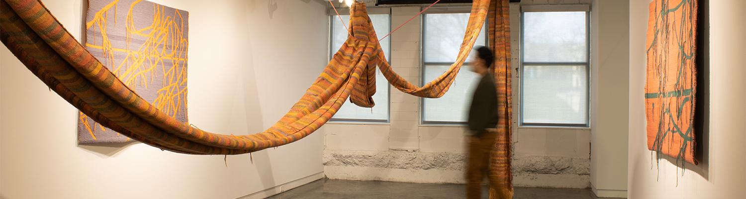 Figure walking through large hanging textile exhibit