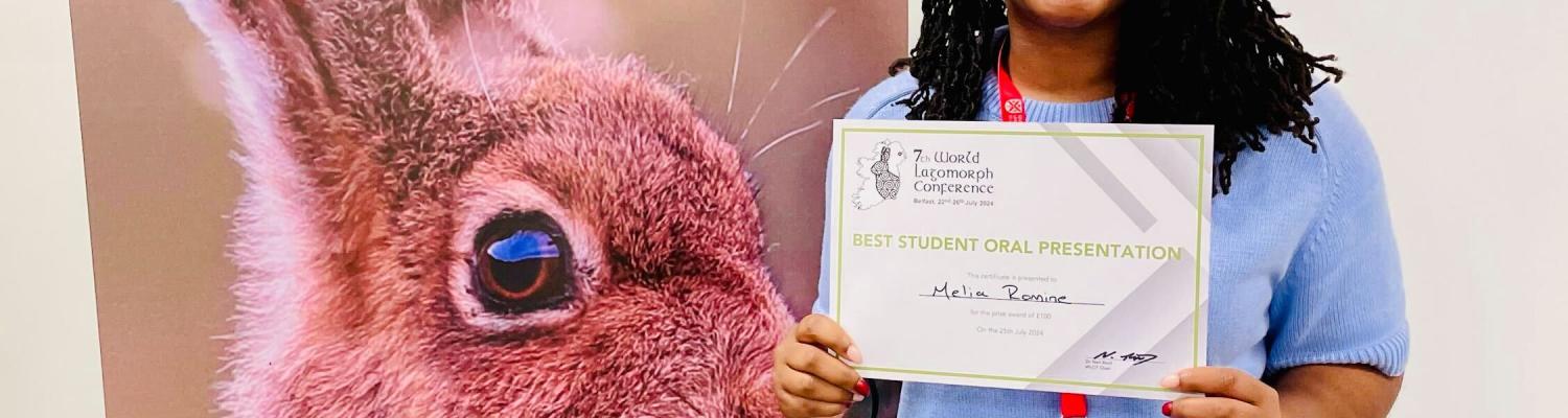 Student holding conference presentation award