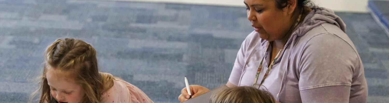 A teacher assisting young students in a coding project.