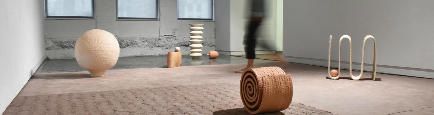 Blurred figure walking through gallery with abstract ceramic objects