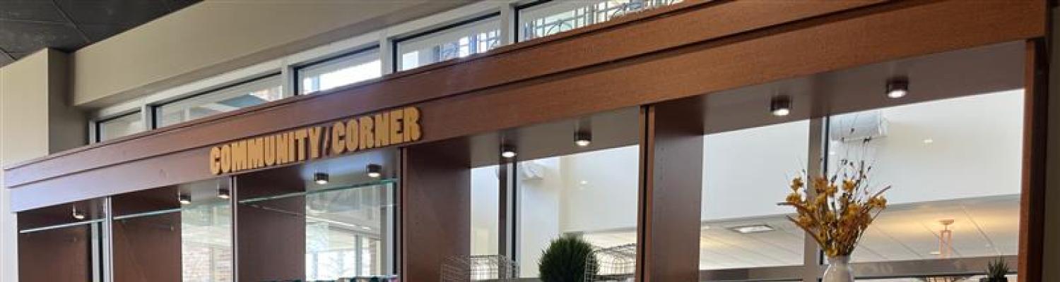 Large display case holding various items/products with the words "Community Corner" at the top of the case