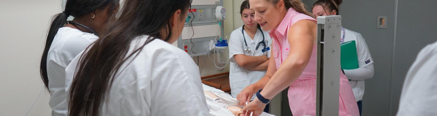 Nursing students working with a faculty member in the simulation lab