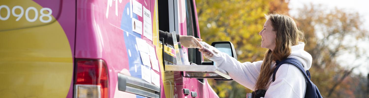 Smiling student being handed their order out of the window of the Daisey Pops food truck