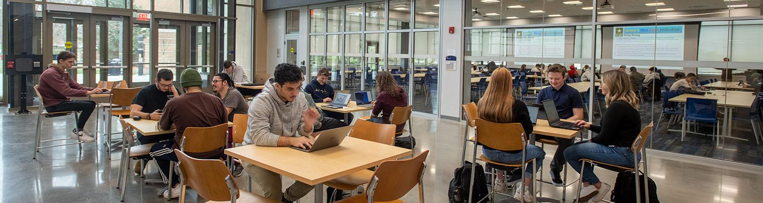 Inside the Aeronautics & Engineering building main atrium where several students are seated at raised tables.
