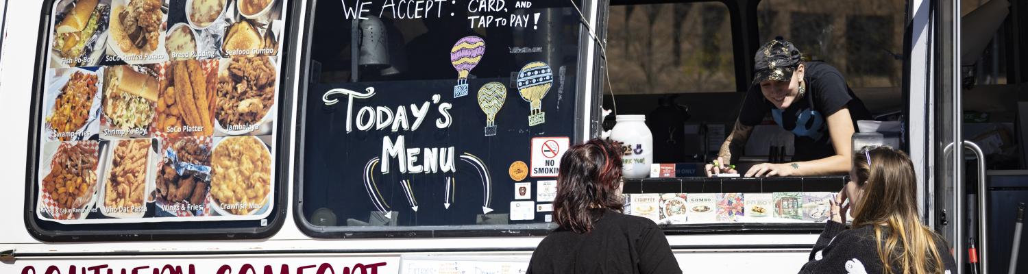 Food truck employee helping customers through the window of the Southern Comfort: New Orleans Style food truck