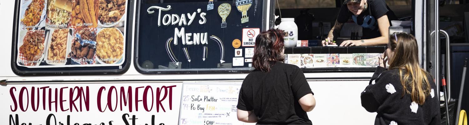 Food truck employee helping customers through the window of the Southern Comfort: New Orleans Style food truck