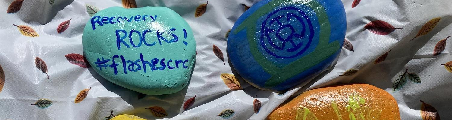 Painted rocks with one of them including a promotion of the Collegiate Recovery Community.