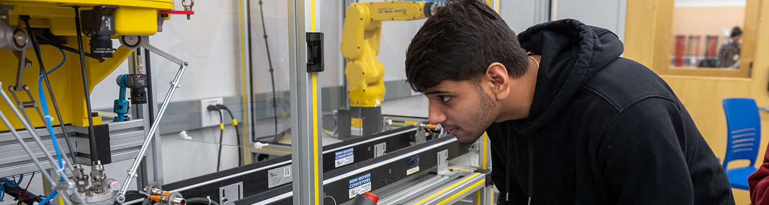 A student observes the workflow of two industrial robots