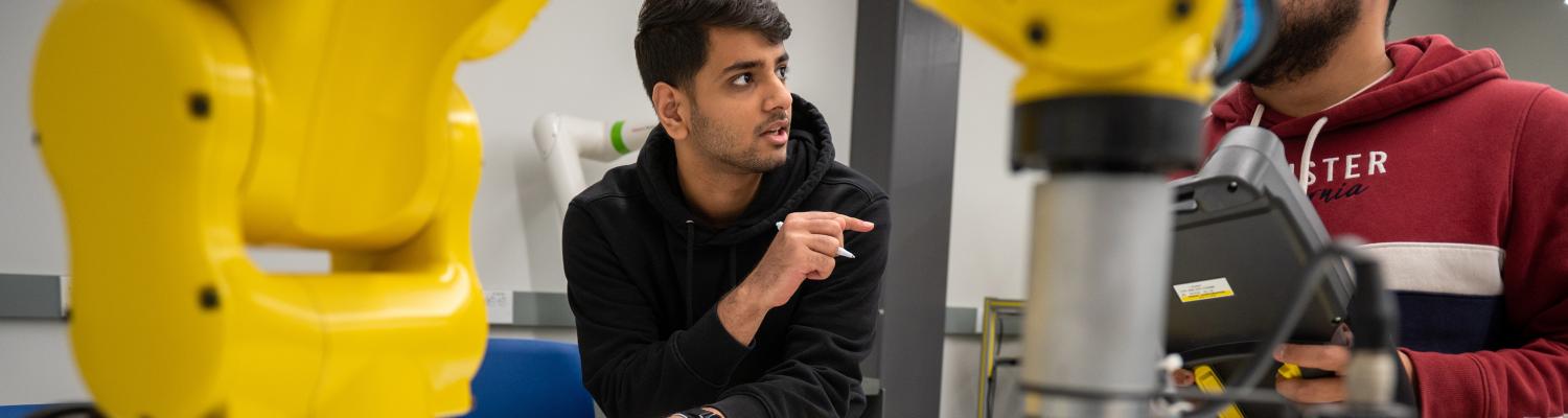 Students discuss the function of a FANUC robot