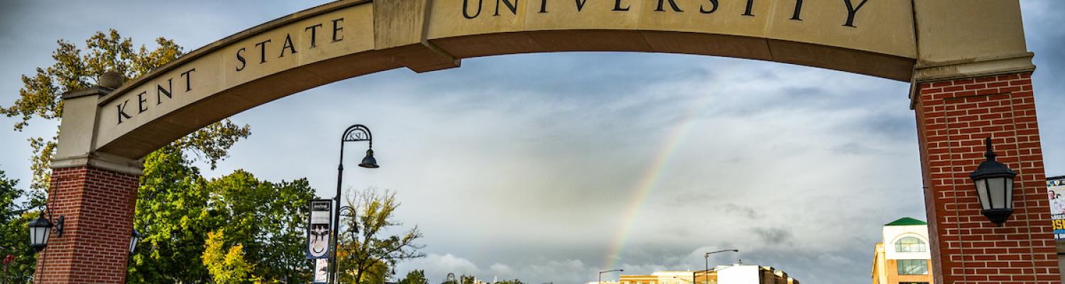 Closeup of the ������Ƶ State Arch, reading ������Ƶ, with a partially cloudy sky and a rainbow in the background